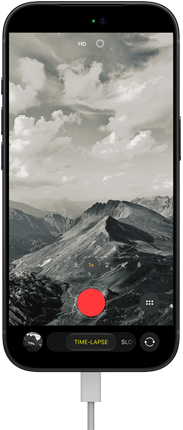 iPhone 18 Pro, преден екстериор, показващ планински пейзаж, с интерфейс на камерата в Time-Lapse режим, кабел е закачен към зарядния порт