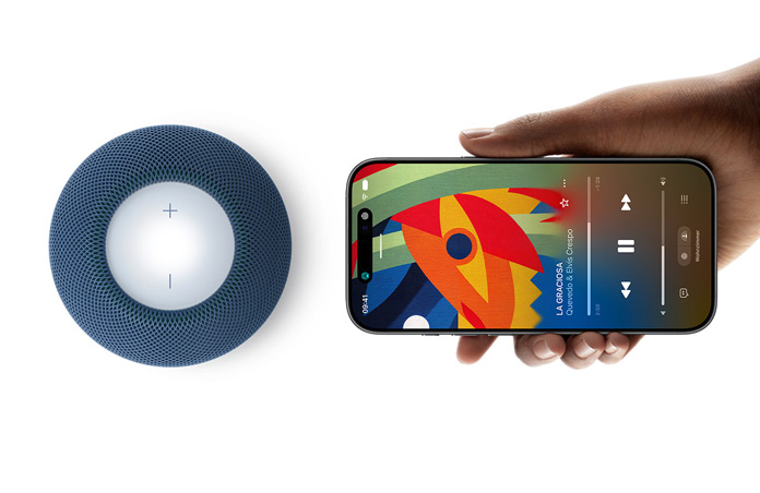 HomePod mini 2 und iPhone: Eine Hand hält ein iPhone neben einen HomePod mini 2 in Blau, um das Feature Handoff zu zeigen