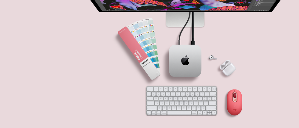 Mac mini, ülaltvaade, hõbedane alumiinium, ümarad nurgad, keskel läikiv must Apple’i logo, juhtmega ühendatud, Studio Display osaliselt nähtav, AirPods 4, avatud, Pantone’i värvinäidised ning numbriklahvistik ja hiir