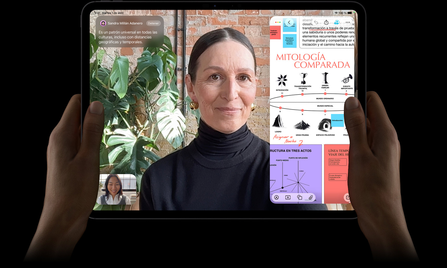 iPad Pro, parte delantera exterior, color negro espacial, las manos izquierda y derecha de una persona sujetándolo en horizontal, esquinas redondeadas, marco de la pantalla negro, la pantalla muestra una conversación de FaceTime traducida en tiempo real y una app educativa con una presentación sobre mitología comparada con texto, diagramas y notas escritas a mano