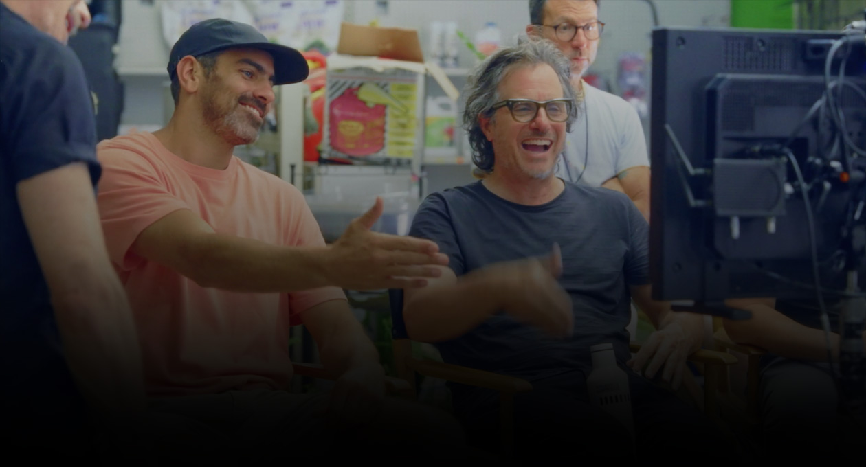 ภาพของผู้สร้างภาพยนตร์ชายสองคนนั่งดูและทำท่าทางไปที่หน้าจอโปรเจ็กเตอร์