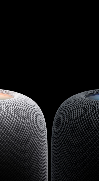 Two HomePod speakers, positioned side by side, cylindrical, rounded edges, glowing touch surface on top, white color and midnight color
