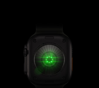 Apple Watch Ultra 4 的背面，黑色鈦金屬錶殼，多個圓形感應器發出綠色光，機身左側有數碼錶冠和凸起的側邊按鈕