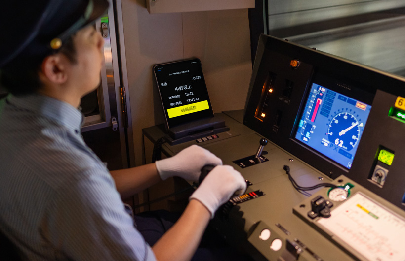 Um iPad com estações e horários está ao lado do painel de controle, onde um operador de trem trabalha.