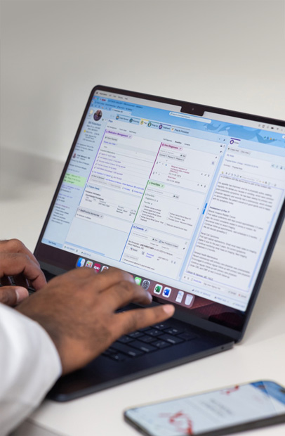 Profissional da saúde consulta registros eletrônicos de saúde em um MacBook Pro.