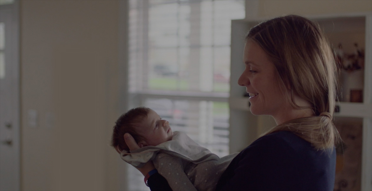 En mamma som ler mot sitt nyfödda barn.