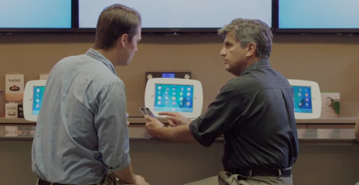 Dos hombres sentados en el O Bar miran la pantalla de un iPhone.