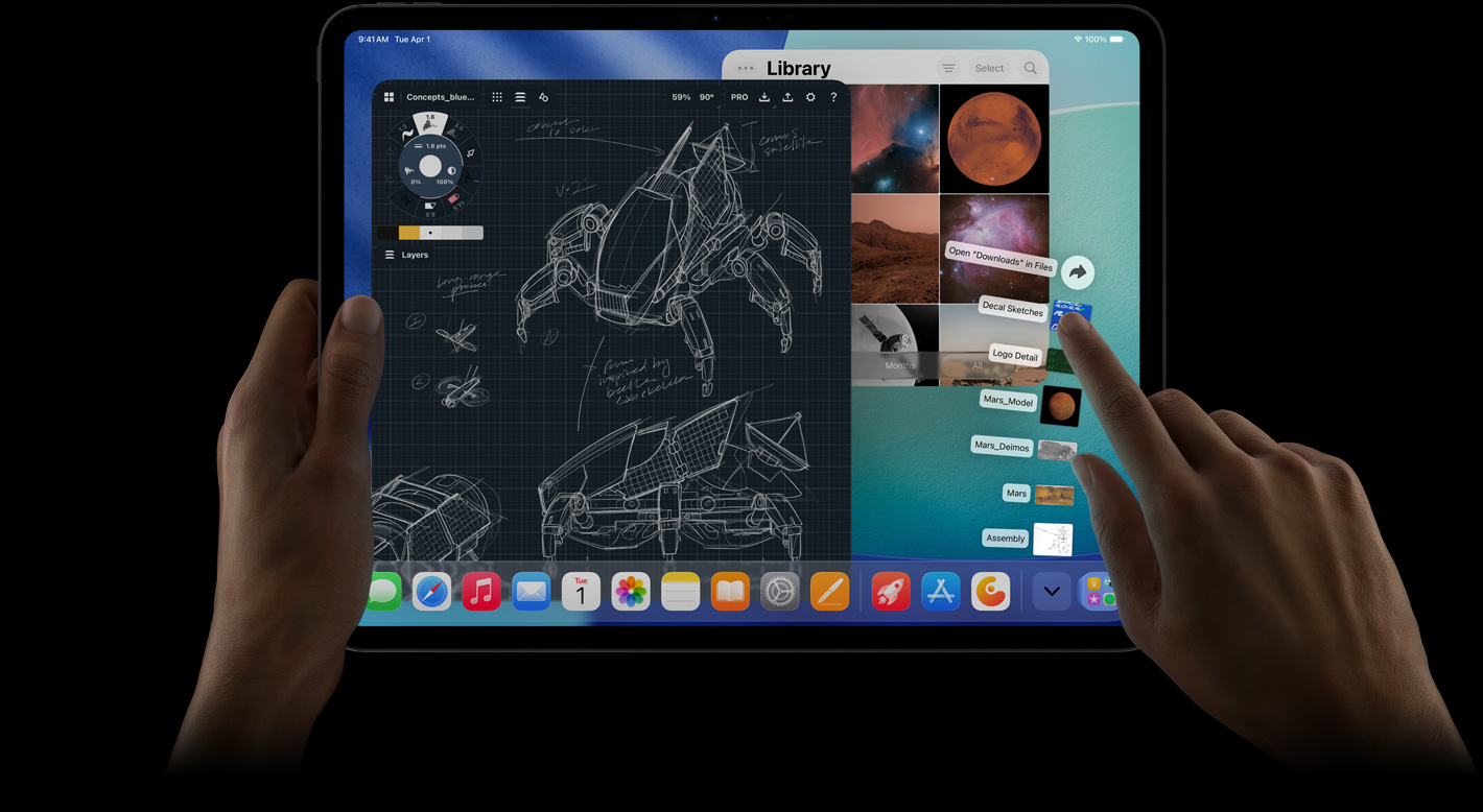 iPad Pro, face avant, orientation paysage, main droite manipulant les fichiers du dossier Téléchargements en éventail, écran affichant l’interface iPadOS 26 avec plusieurs apps ouvertes, dont une app de retouche photo avec des plans détaillés de robots et des annotations manuscrites ainsi que plusieurs étapes de conception, et la photothèque