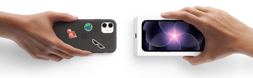 Due mani che si scambiano un iPhone 11 usato con custodia in silicone coperta di adesivi sul retro e un iPhone 17e nuovo ancora nella sua confezione