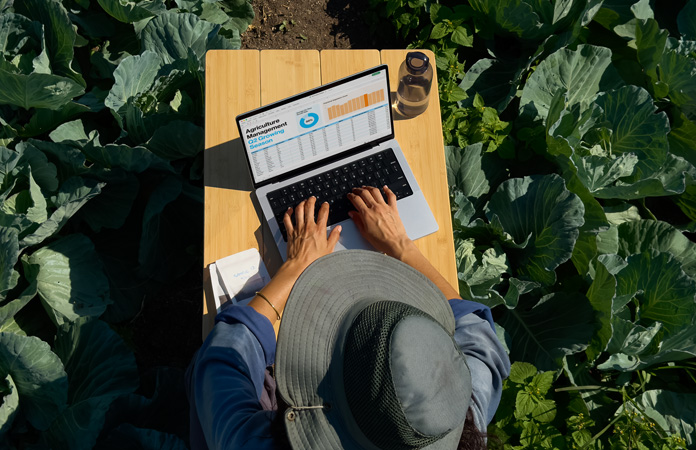 Una persona sentada al aire libre usa una MacBook Pro configurada con opción de pantalla con acabado nanotexturizado, donde se aprecia la reducción del reflejo