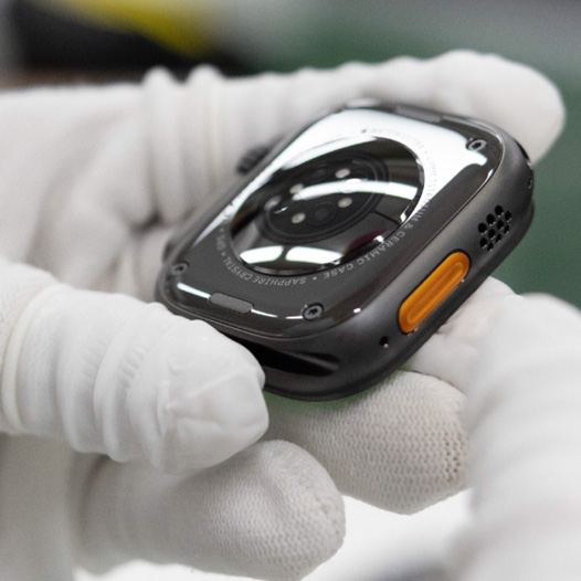 Main gantée tenant un boîtier d’Apple Watch à l’envers