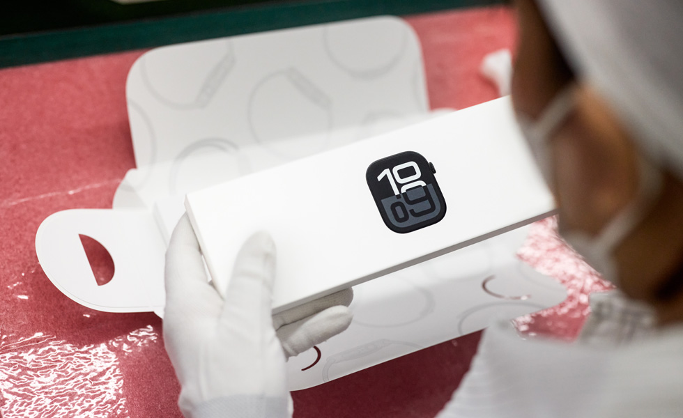 Vue en plongée d’une personne portant un masque en train d’emballer une Apple Watch