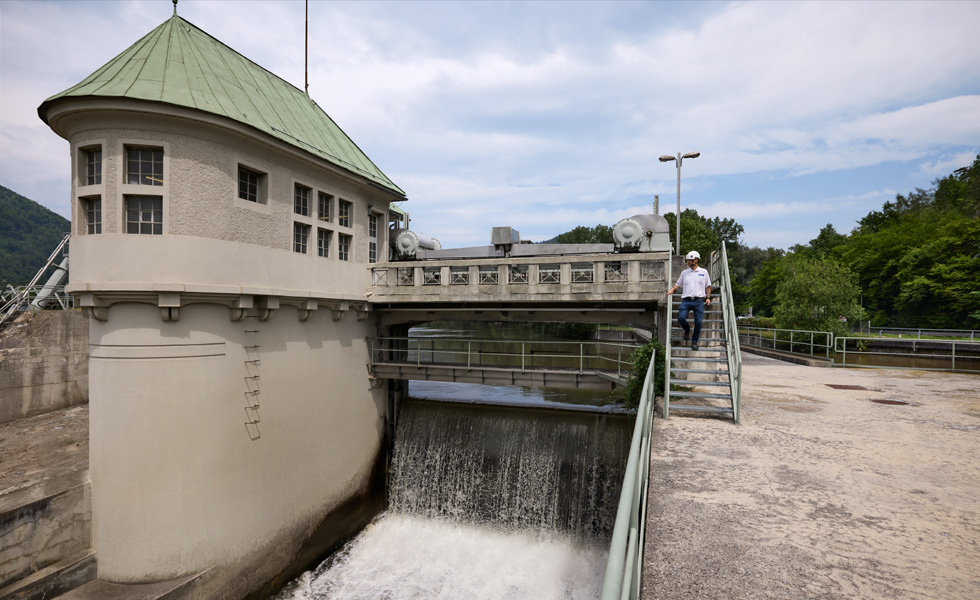 Une personne portant un casque de protection descend les escaliers d’un pont dans une centrale hydroélectrique