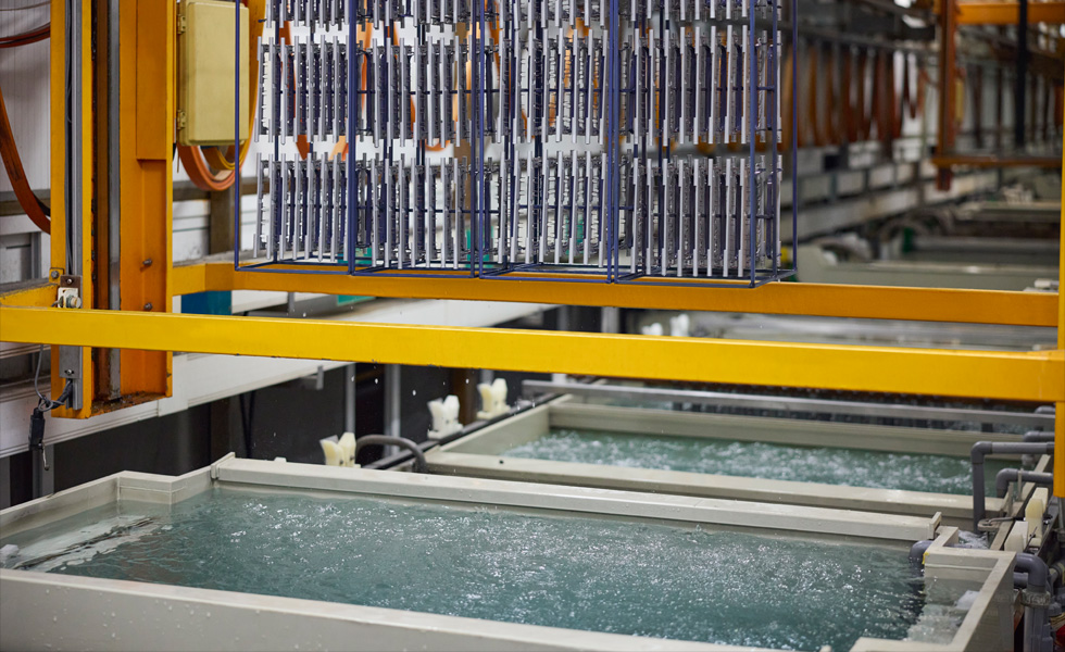 Une machine de la chaîne de fabrication de composants laissant couler de l’eau dans une cuve située en dessous
