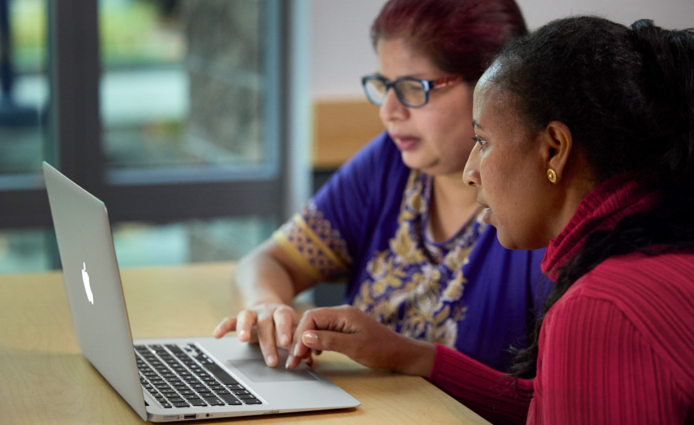 Deux personnes partageant un ordinateur portable pour collaborer ou apprendre