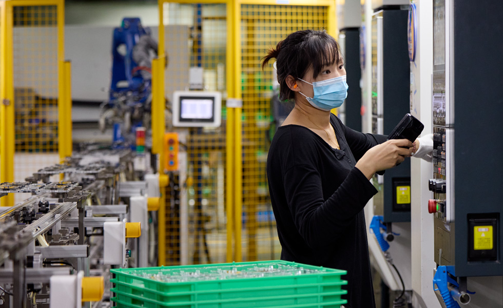 Une employée fait fonctionner une machine dans une usine de fabrication de composants