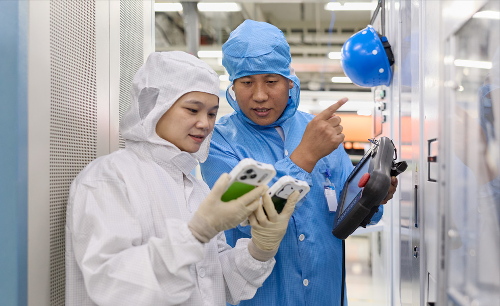 Two people in full-body work suits collaborate over two iPhone devices